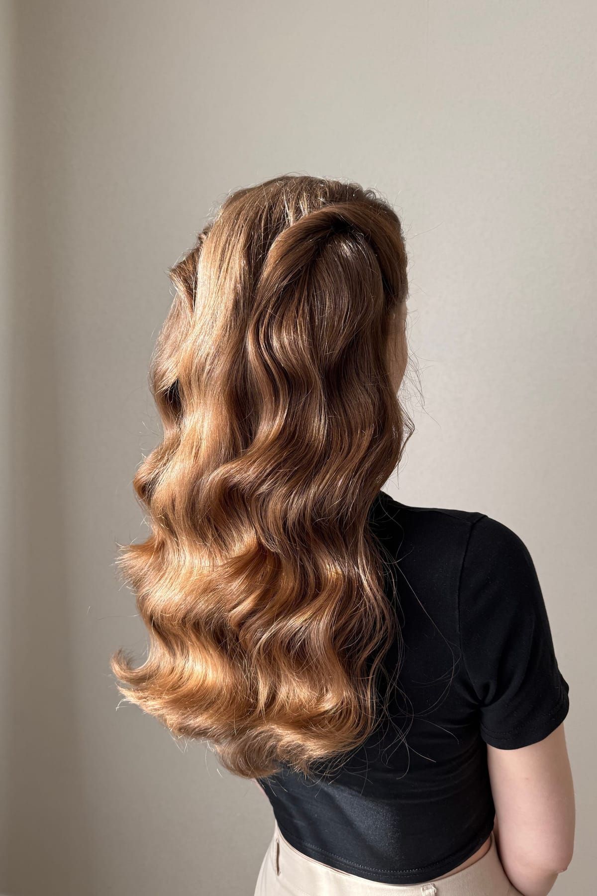 A woman seen from behind with long, glossy brown waves falling down her back
